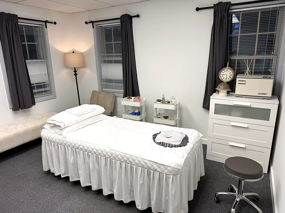 Treatment room at our Chain Bridge Rd clinic with a skirted table, folded towels, and soft lighting