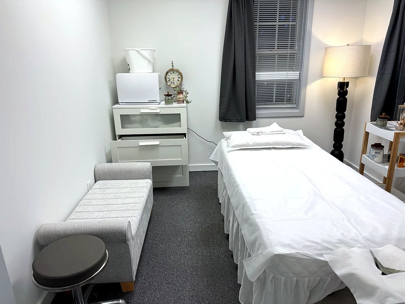Private treatment room at Harmony Acupuncture & Wellness Spa in McLean — made-up treatment bed with folded towel, dresser, lamp, and bench